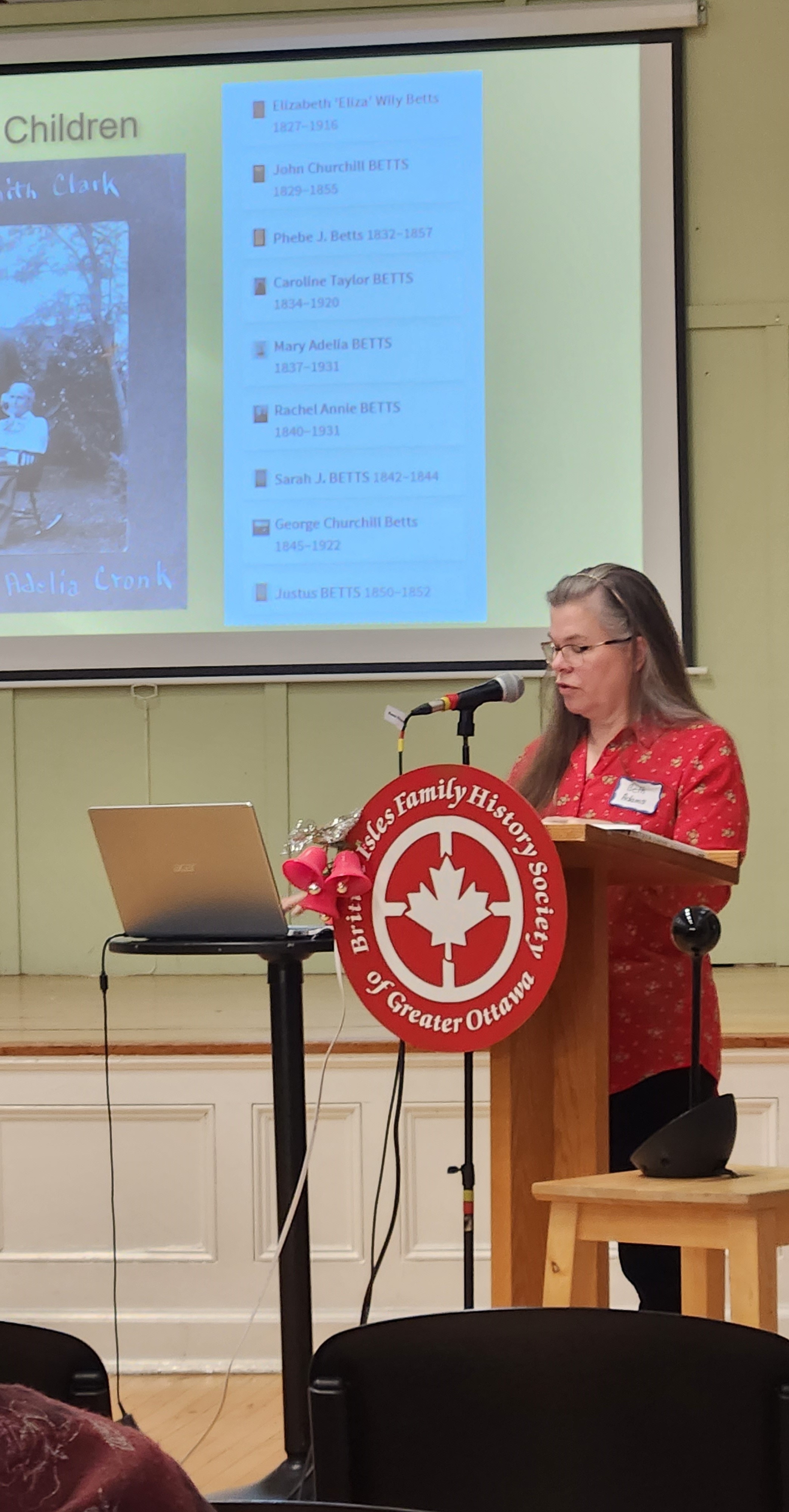 speaker standing at a podium presenting a slideshow