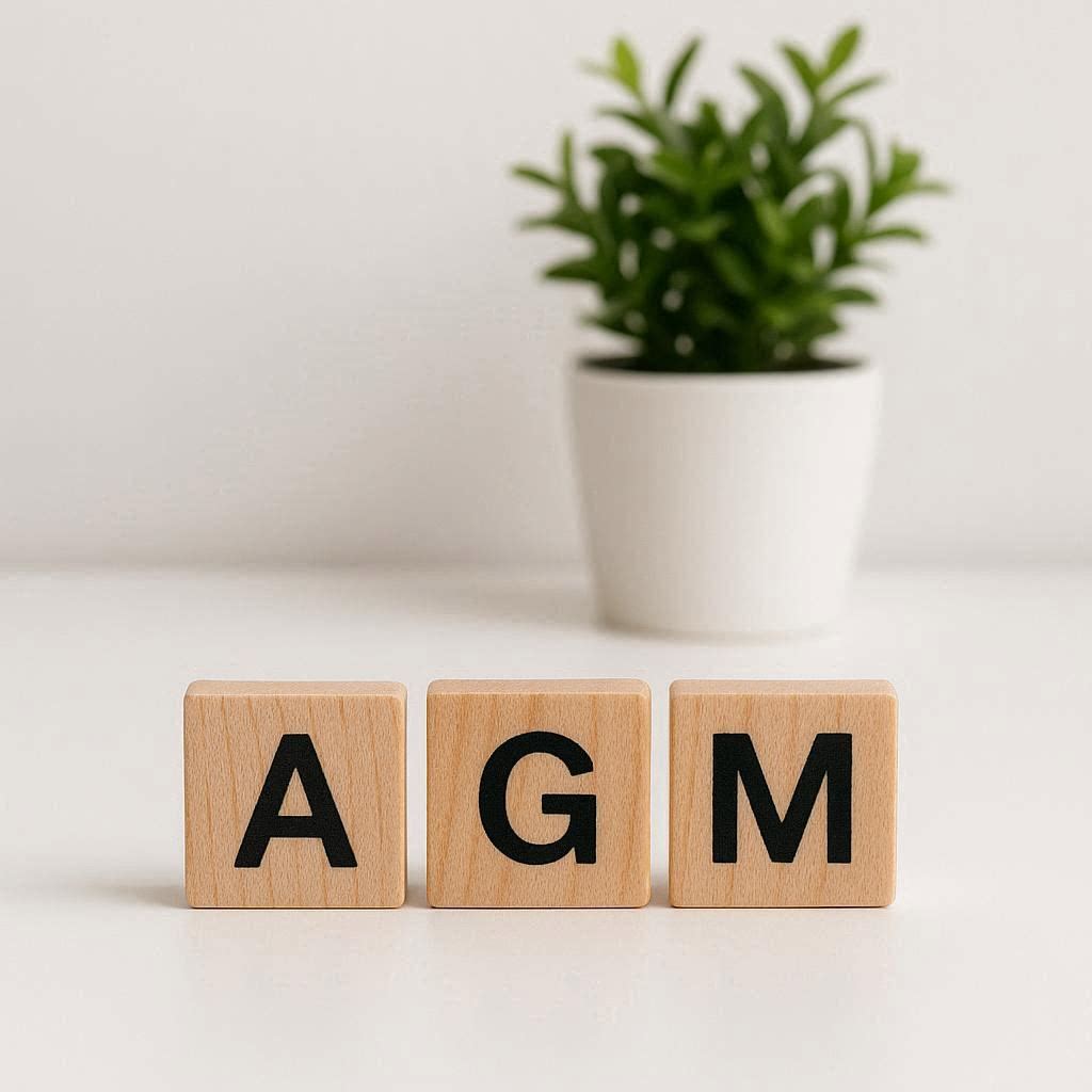 letters agm on wooden tiles with a potted plant in the background
